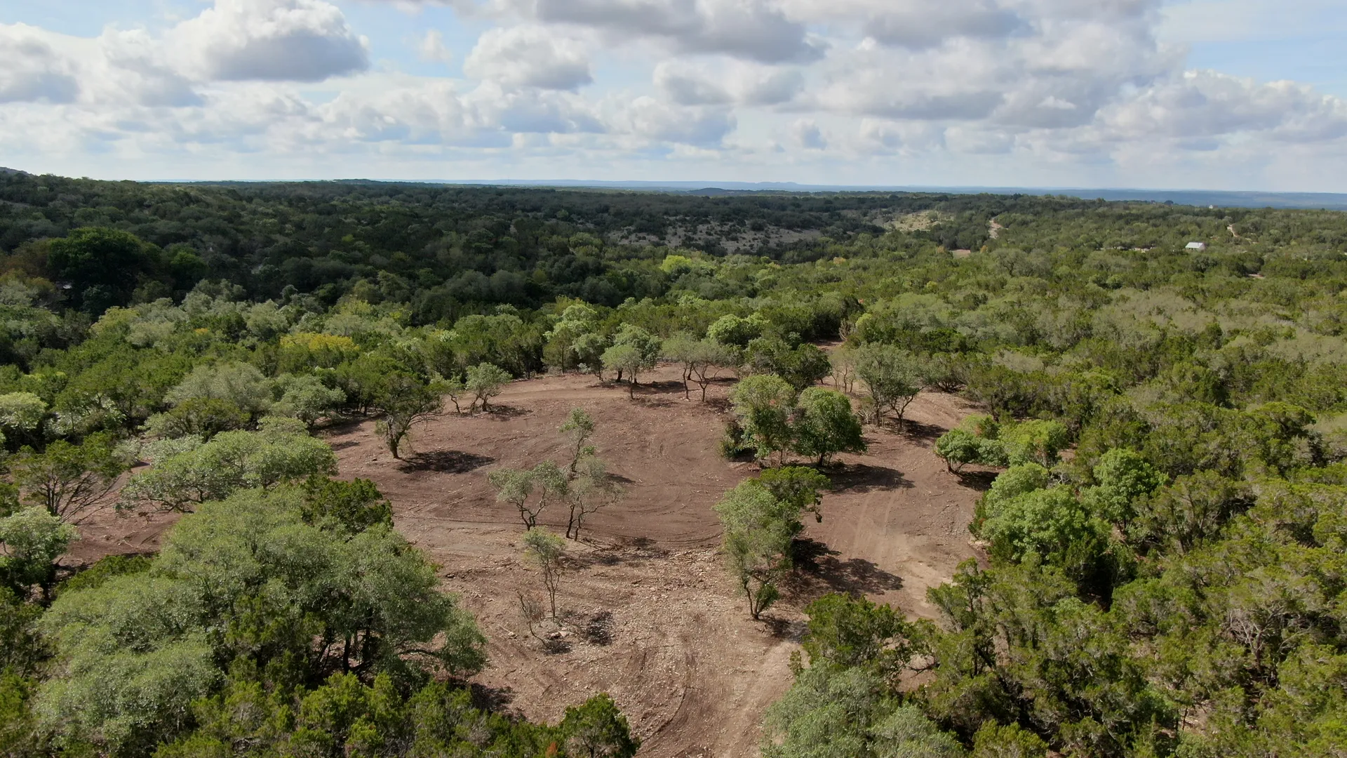 Oblique aerial view of open ground and trees on the Wimberley property.